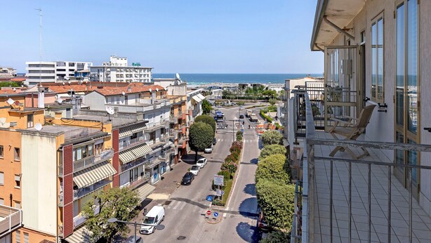 A high-rise building with a view of a coastal street and the sea.