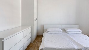 A minimalist bedroom with a bed, a wardrobe, and a door.