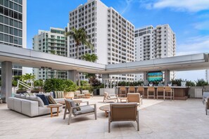 An outdoor lounge area with seating, a bar, and a TV screen. - Brickell Floor 31 Sea View-Free Parking by Palermo Home (Miami)