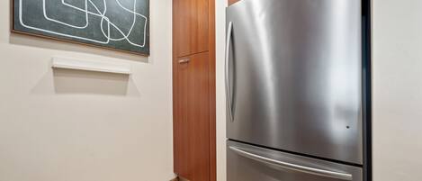 A kitchen with a stainless steel refrigerator, wooden cabinets, and a wall-mounted abstract art piece.