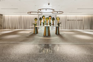 A modern interior with a round glass table surrounded by metallic stands, a ceiling with circular light fixtures, and a backdrop with the text 'BRICKELL ARCH'. - Brickell Floor 31 Sea View-Free Parking by Palermo Home (Miami)