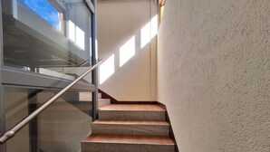 Eine Treppe mit Glasgeländern und einer strukturierten Wand.