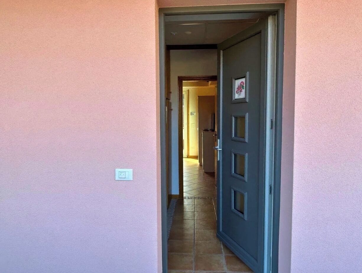 Un couloir avec une porte fermée donnant sur une pièce.