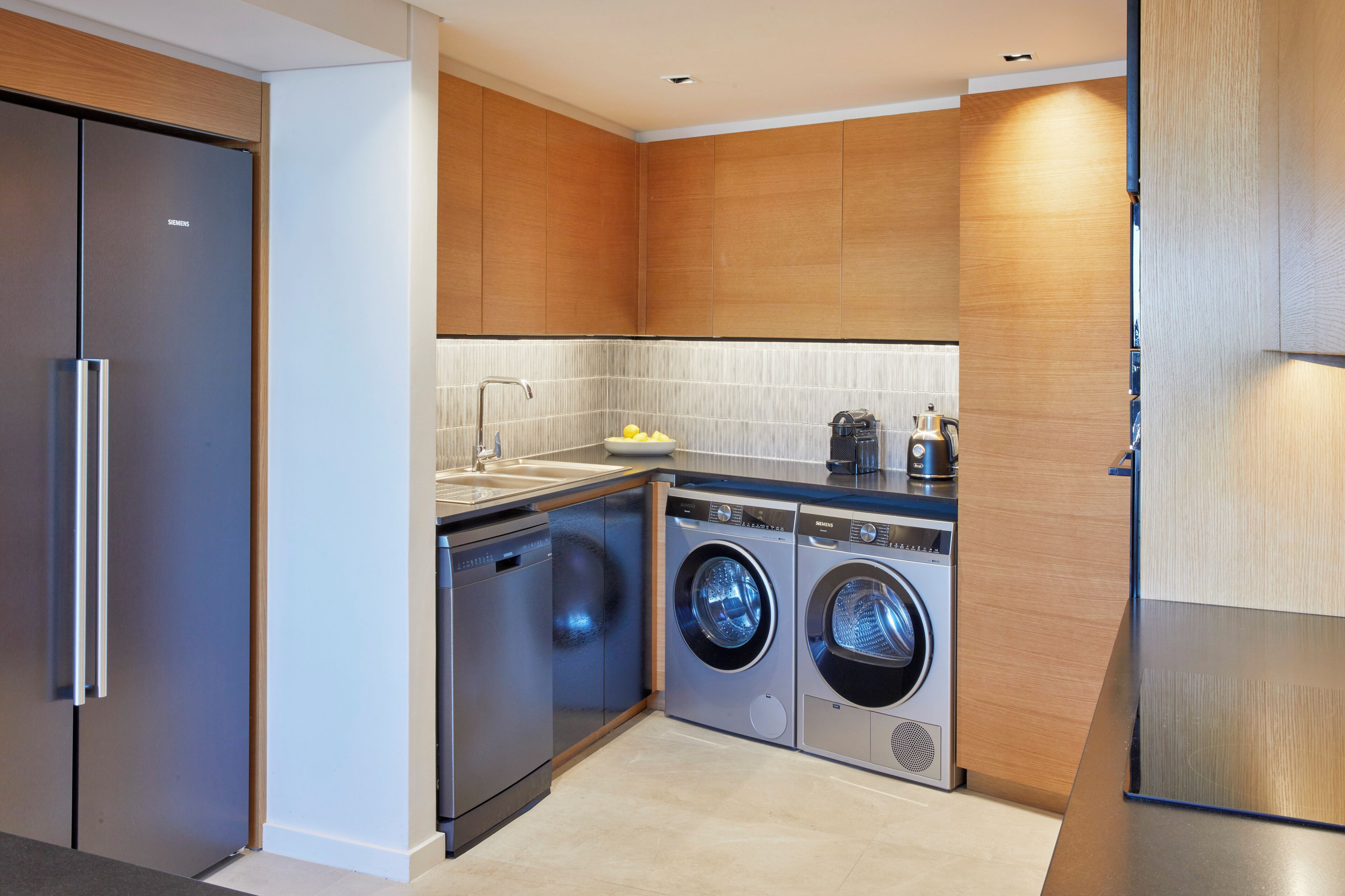 A compact kitchen with a dishwasher, washing machine, and a sink.