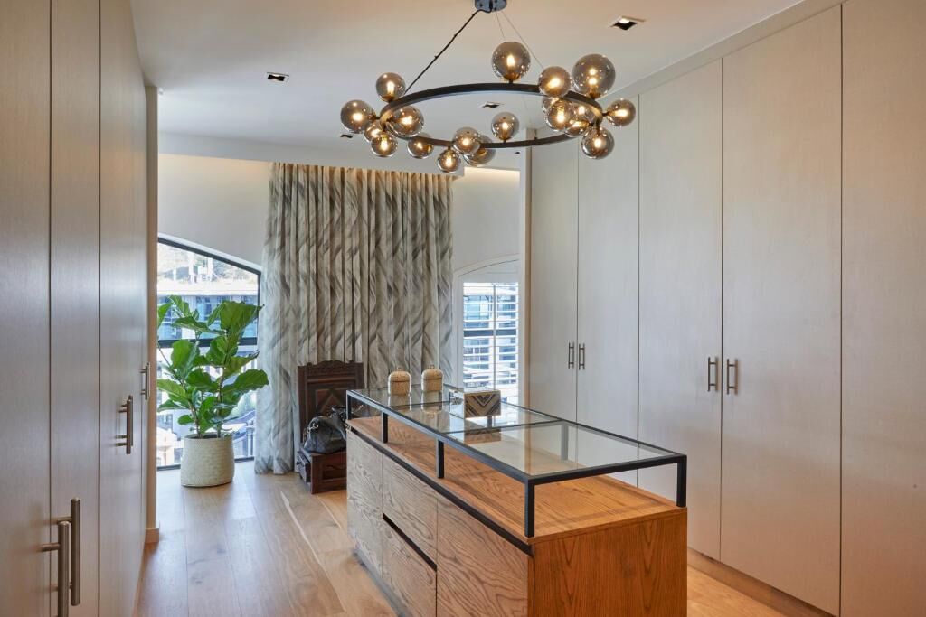A modern kitchen with a glass-top island, stainless steel appliances, and a unique spherical chandelier.