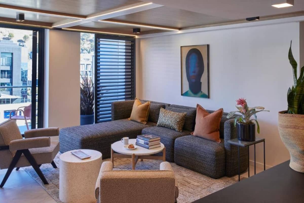 A modern living room with a sectional sofa, a round coffee table, and a large window with blinds.