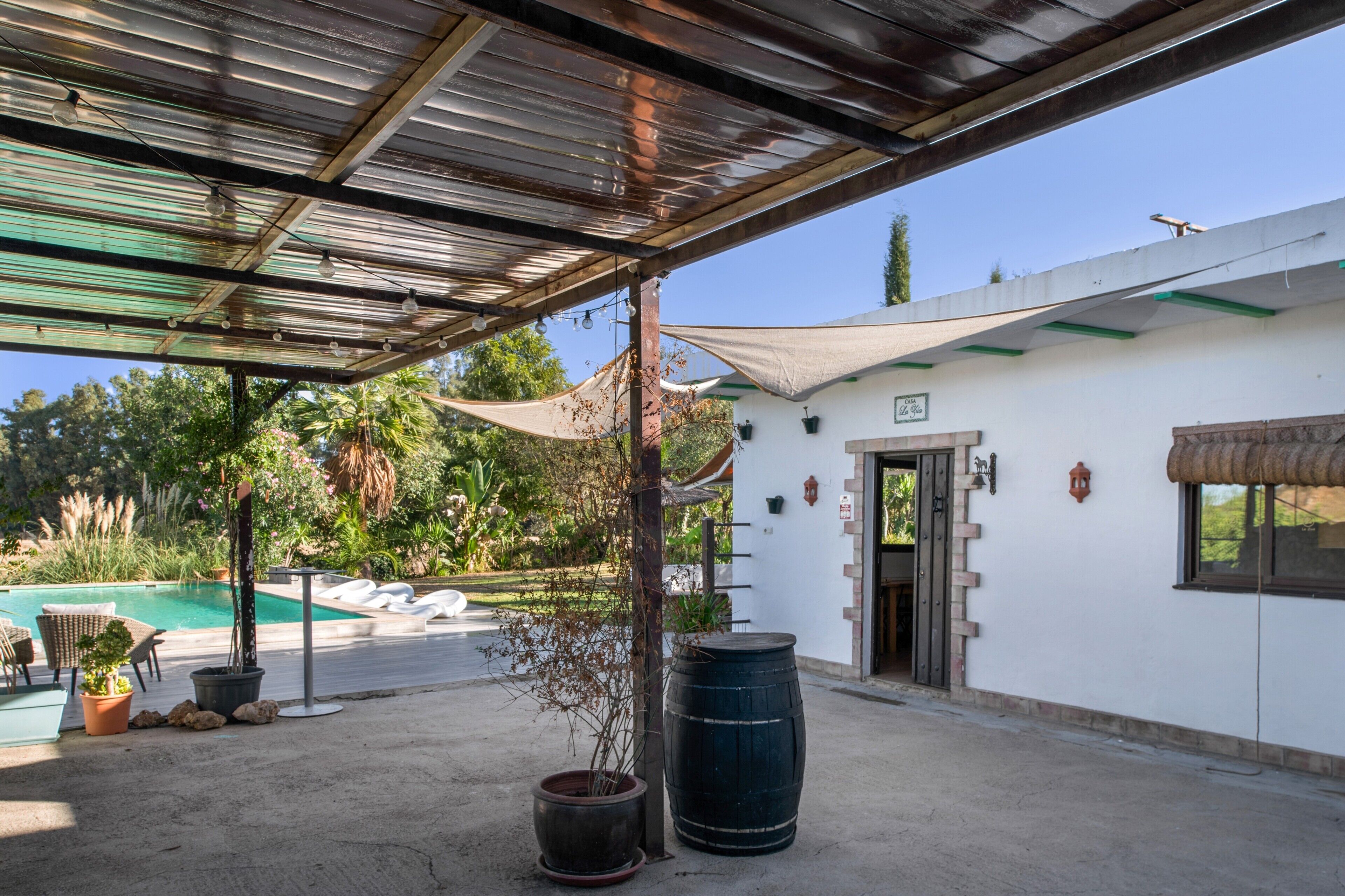 Un espacio exterior cubierto con piscina, sillas de descanso y plantas en macetas.