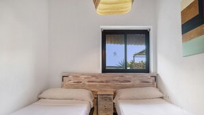 A bedroom with two beds, a window, and a wooden headboard. - Country House 'La Zua' with Private Pool, Wi-Fi and Air Conditioning (Villamartin)