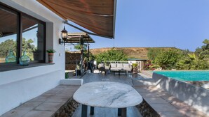 A patio with a marble table, outdoor furniture, a stone wall, and a pool. - Country House 'La Zua' with Private Pool, Wi-Fi and Air Conditioning (Villamartin)