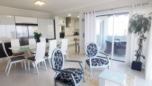 A modern kitchen with white cabinets, a dining area with white chairs and a glass table, and a balcony with a potted plant. - Casa do Mar - Luxury Villa w rooftop SwimSpa (Luz)