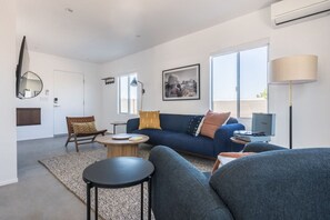 Un salon moderne avec un canapé, des fauteuils, une table basse et un téléviseur.