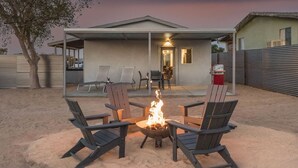 Ein Garten mit Feuerstelle, Sitzgelegenheiten im Freien und einer überdachten Terrasse.