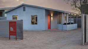 Ein modernes Gebäude mit flachem Dach, großen Fenstern und einer roten Tür.