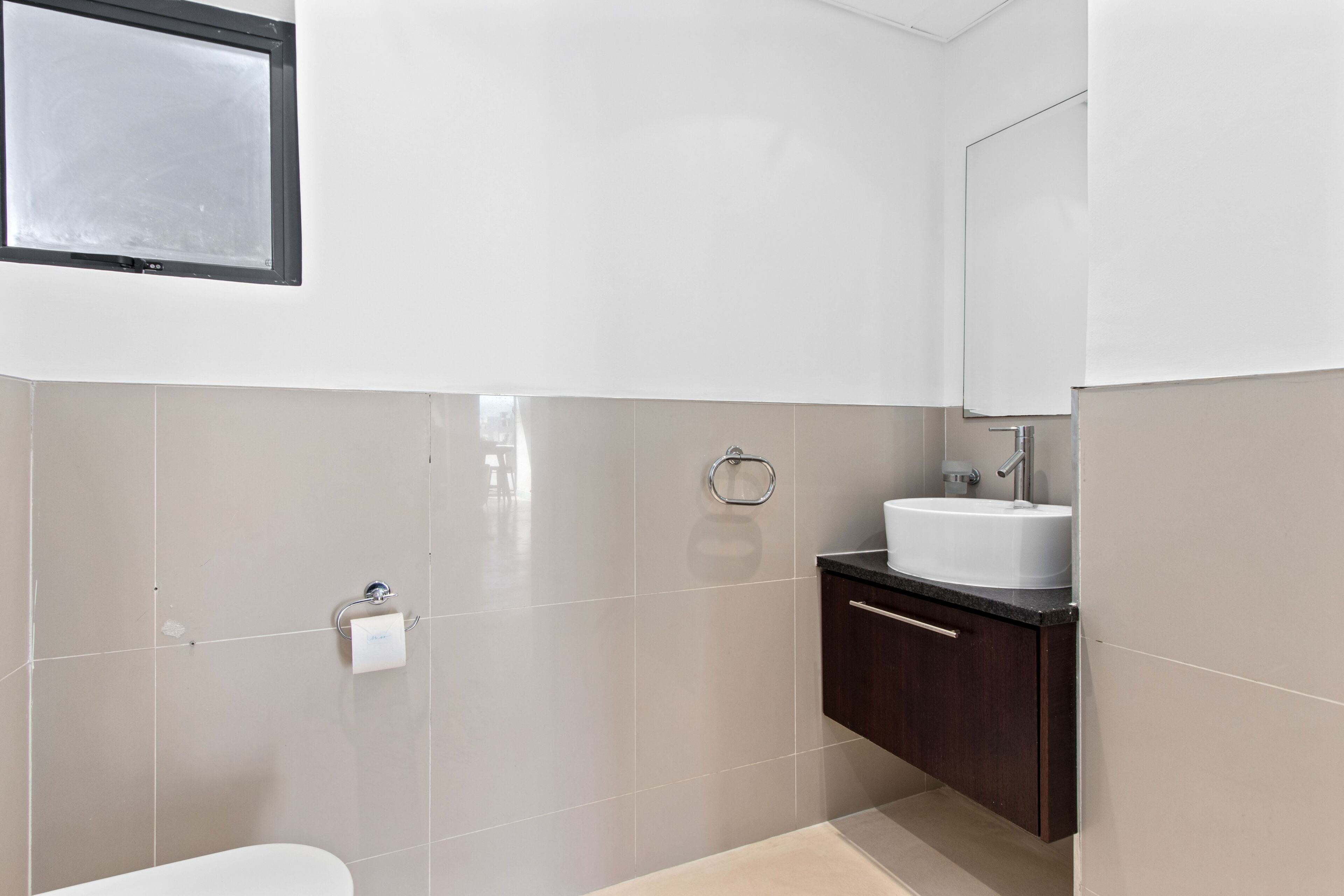 Un baño moderno con inodoro, lavamanos y espejo.