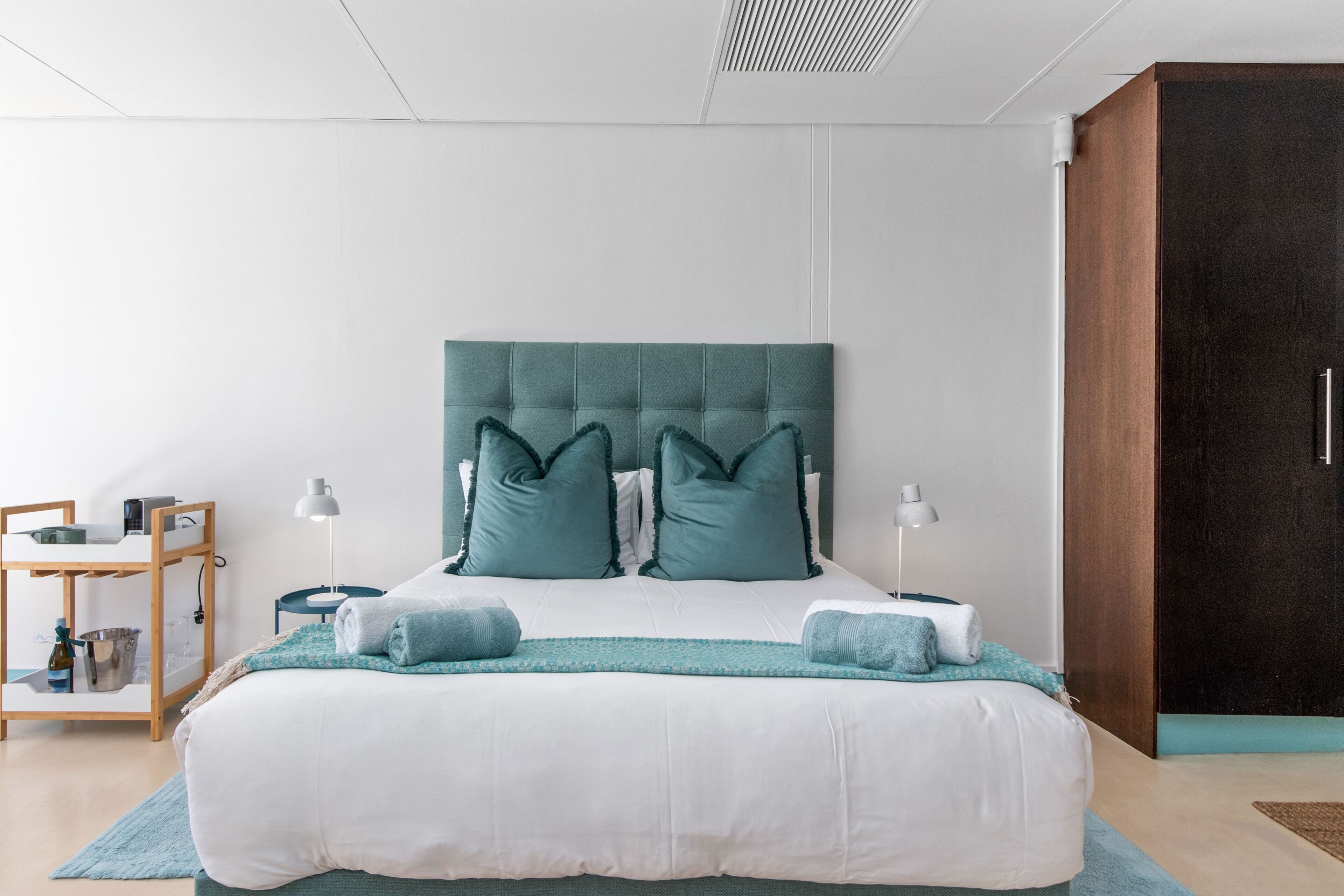 Ein modernes Schlafzimmer mit einem großen Bett, zwei Kissen, einem Nachttisch und einem Kleiderschrank.