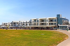 A modern hotel with multiple floors, outdoor seating areas, and a grassy courtyard. - Eden on the Bay 190 (Cape Town)