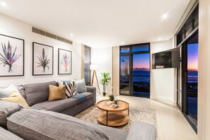 A modern living room with a grey sofa, a round wooden coffee table, and framed botanical prints on the wall. - Eden On The Bay 168 (Cape Town)