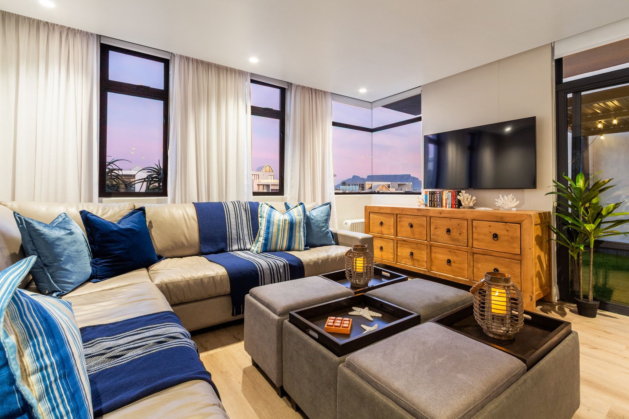 Una sala moderna con un sofá seccional, un mueble de madera y un televisor.