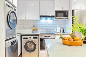 A modern kitchen with built-in appliances, including a microwave, oven, and dishwasher. - Eden On The Bay 102 (Cape Town)