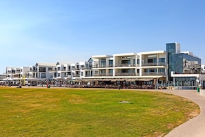 A modern hotel with multiple floors, outdoor seating areas, and a grassy courtyard. - Eden on the Bay 106 (Cape Town)