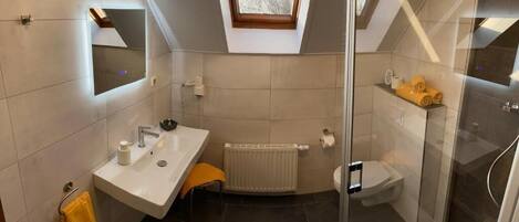 Ein modernes Badezimmer mit Oberlicht, einer Duschkabine aus Glas, einem weißen Waschbecken und einer Toilette.
