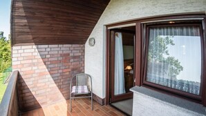 Ein Balkon mit Backsteinboden, einem Korbstuhl und Blick ins Freie.