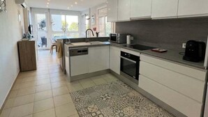 Una cocina moderna con armarios blancos, horno integrado y microondas.