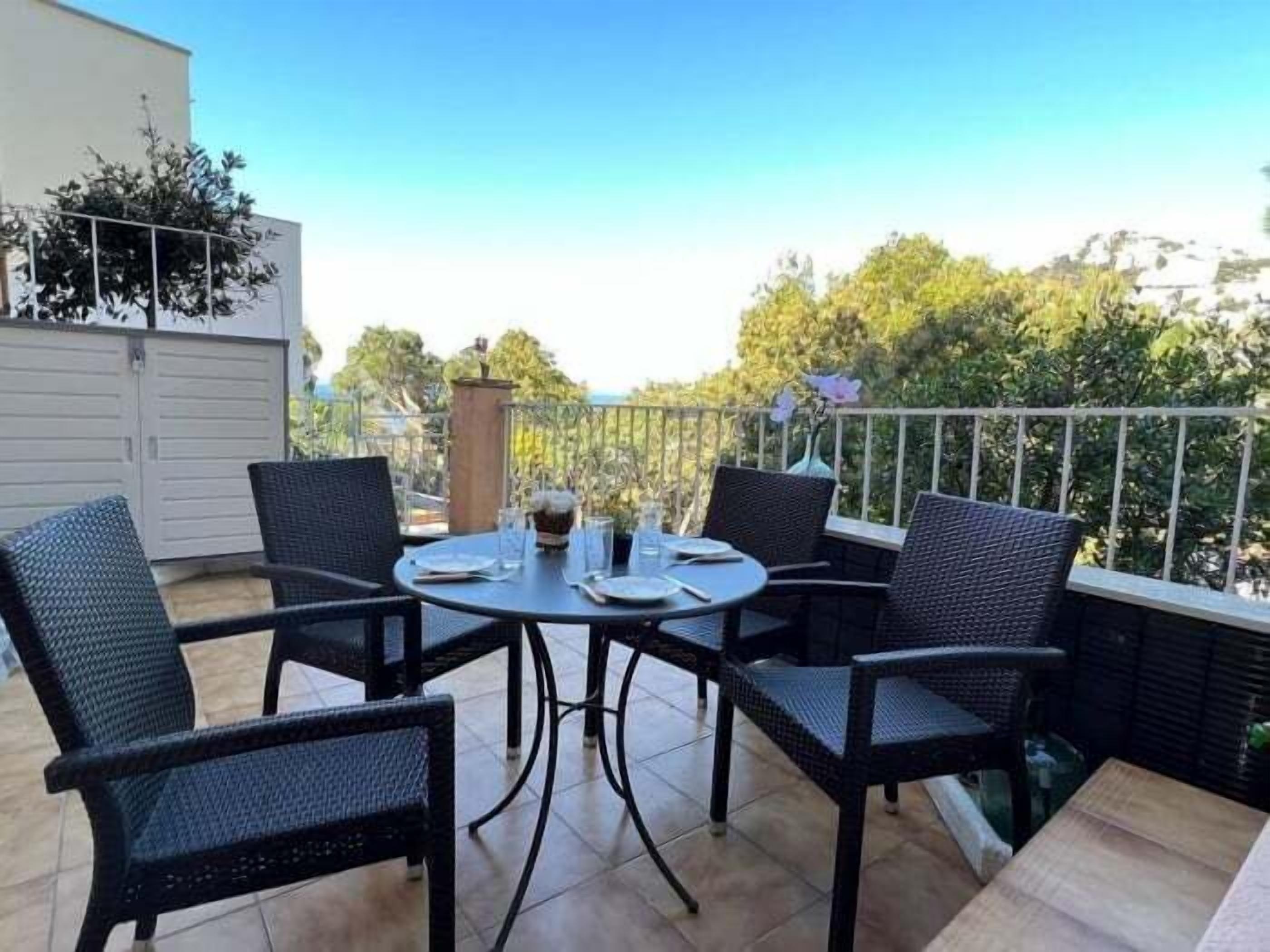 A patio with a round table and four chairs, surrounded by a metal railing.