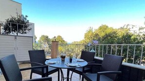 Un patio con una mesa redonda y cuatro sillas, rodeado por una barandilla de metal.