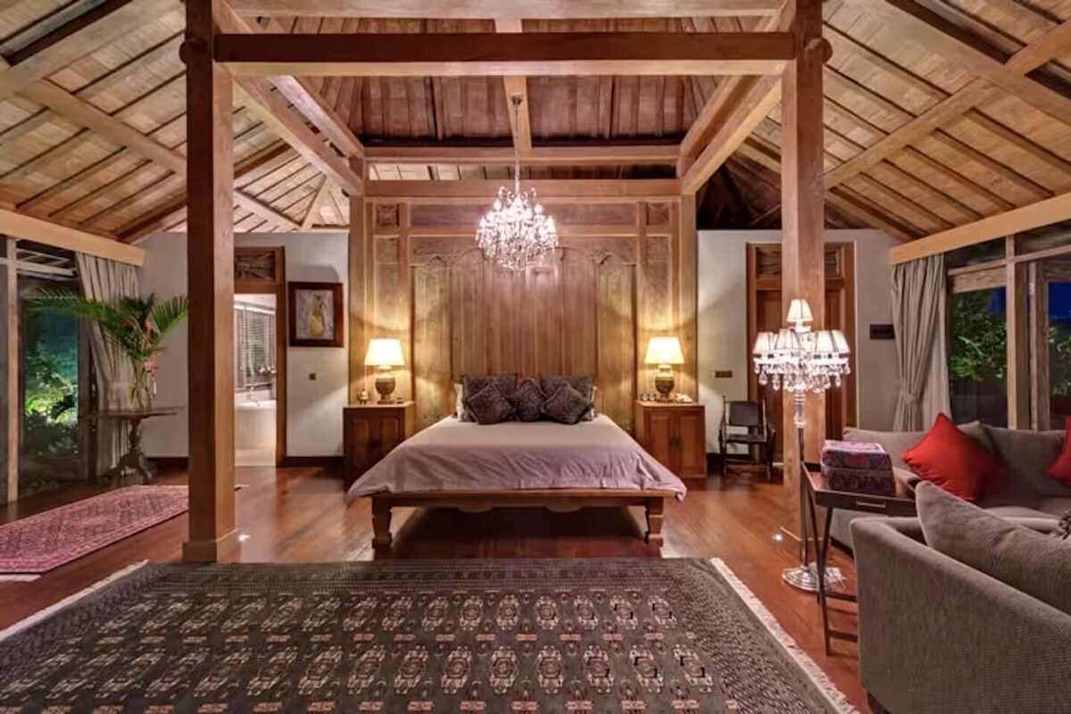 Ein geräumiges Schlafzimmer mit einem großen Bett, Holzbalken an der Decke und einem Kronleuchter.