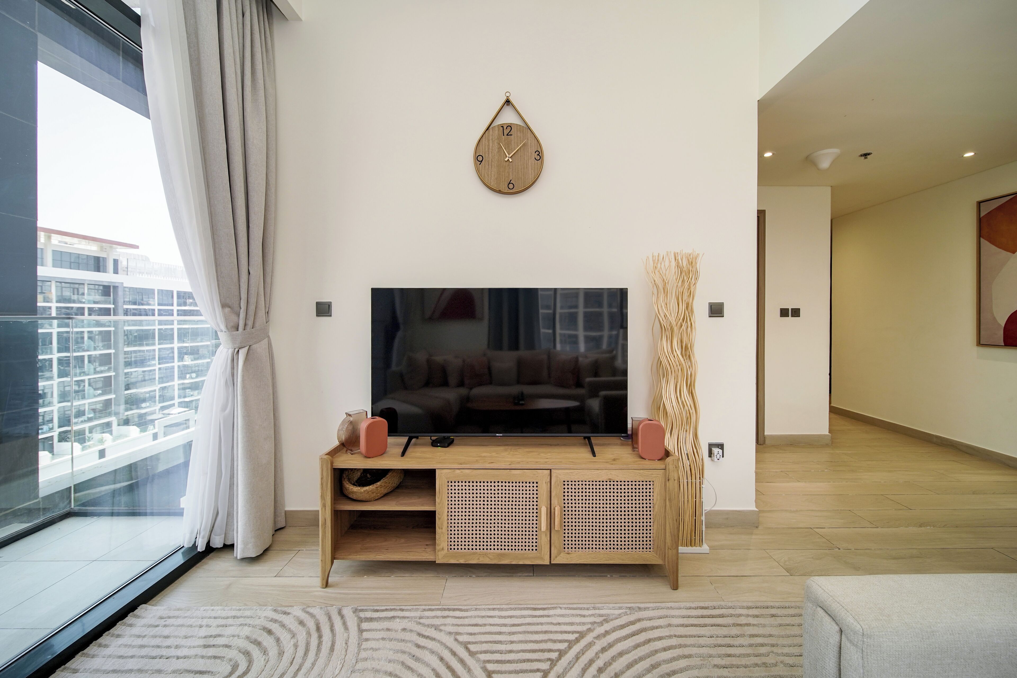 Una sala de estar moderna con un televisor de pantalla plana grande, un mueble de entretenimiento de madera y un reloj decorativo en la pared.