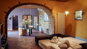 A cozy living area with a sofa, a dining table, and a kitchen visible through an archway.