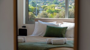 Un letto rifatto con cuscini bianchi e verdi, una coperta a maglia verde e due asciugamani piegati.