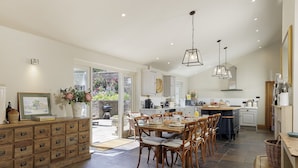 A spacious kitchen with a dining area, featuring a large island, wooden cabinets, and a view of the garden. - Beautifully presented spacious holiday cottage - Gardeners Cottage (Brockhampton)