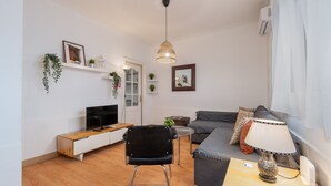 Een woonkamer met een bank, een televisie, een lamp en een stoel.