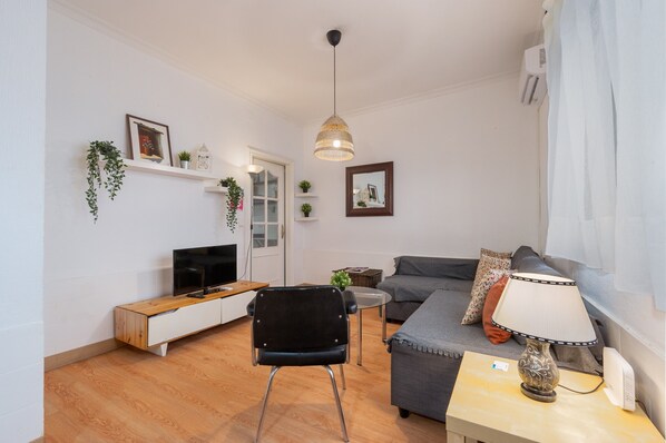 Ett vardagsrum med en soffa, en tv, en lampa och en fåtölj.