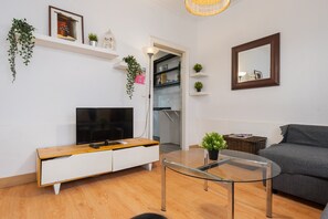 Un soggiorno moderno con una televisione a schermo piatto, un tavolino da caffè in vetro, un divano grigio e un mobile TV bianco.