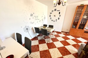 Uma sala de jantar com piso xadrez, uma mesa branca e quatro cadeiras.