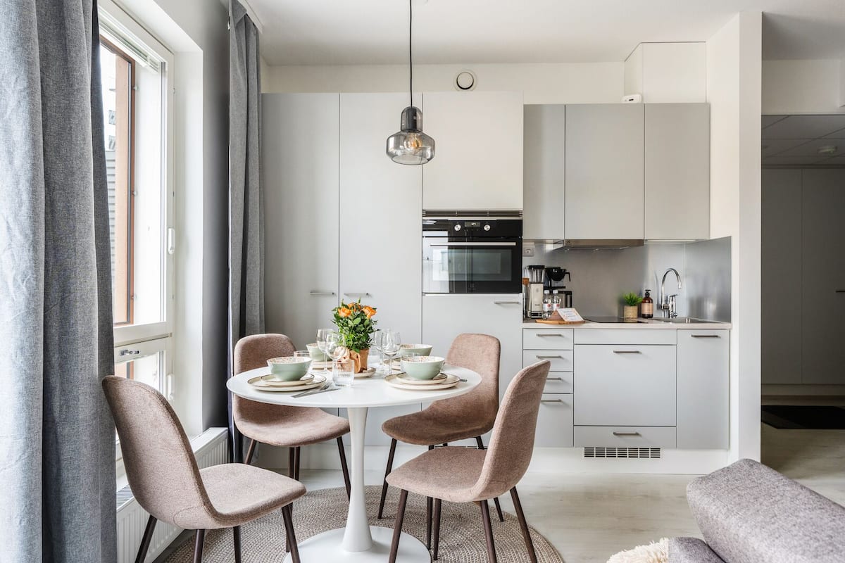 A modern kitchen with white cabinets, a black oven, and a stainless steel sink.
