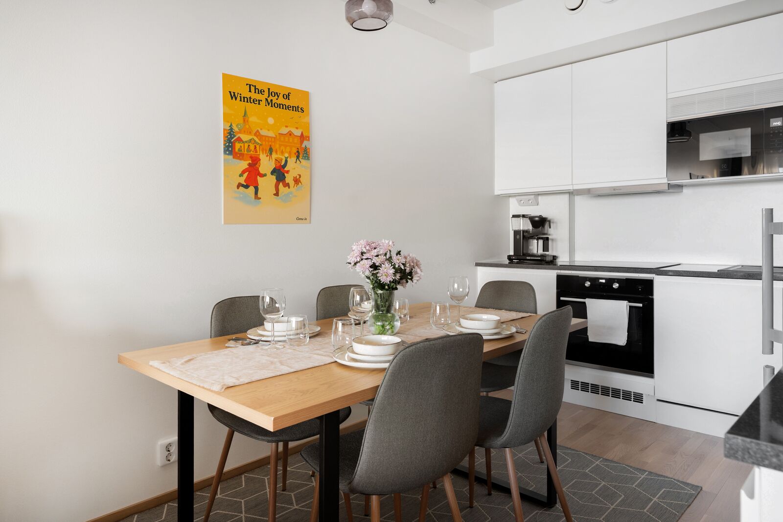 A modern kitchen with white cabinets, a built-in oven, and a dining area with a wooden table set for four.