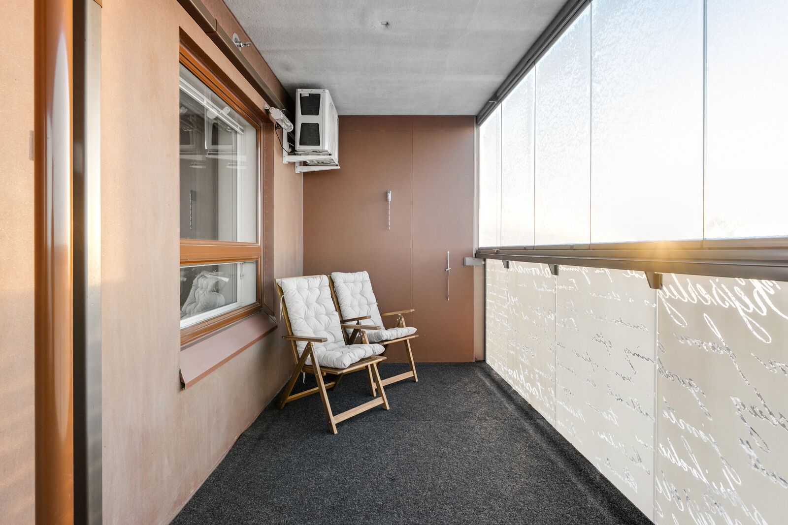 A room with two white cushioned chairs, a window, and a wall with writing.