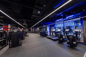 Un gimnasio con equipo cardiovascular y un letrero de neón.