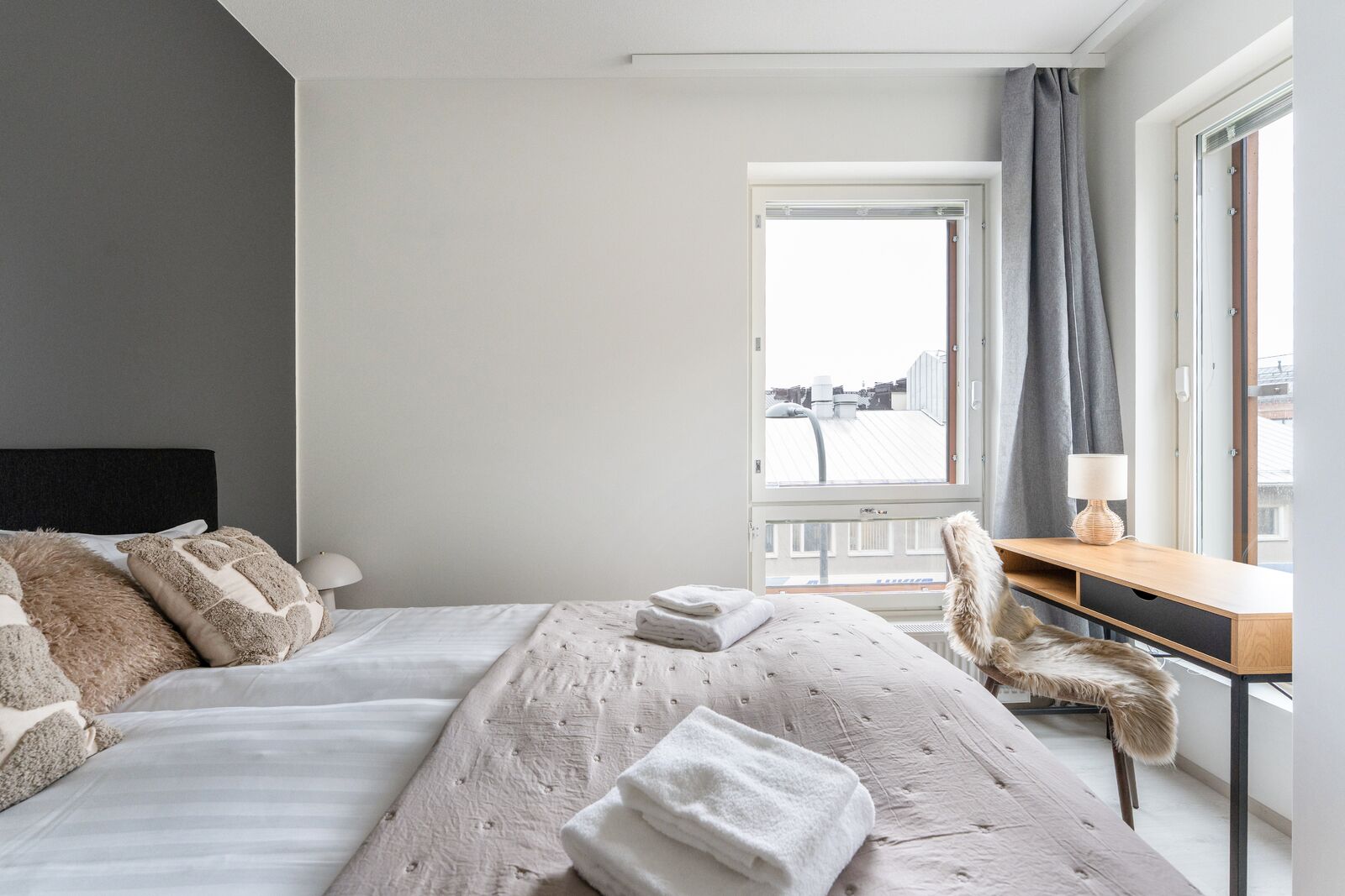 A modern hotel room with a large bed, a desk, and a chair.