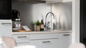Een moderne keuken met een roestvrijstalen spoelbak, een koffieapparaat en een kleine plant in een pot.