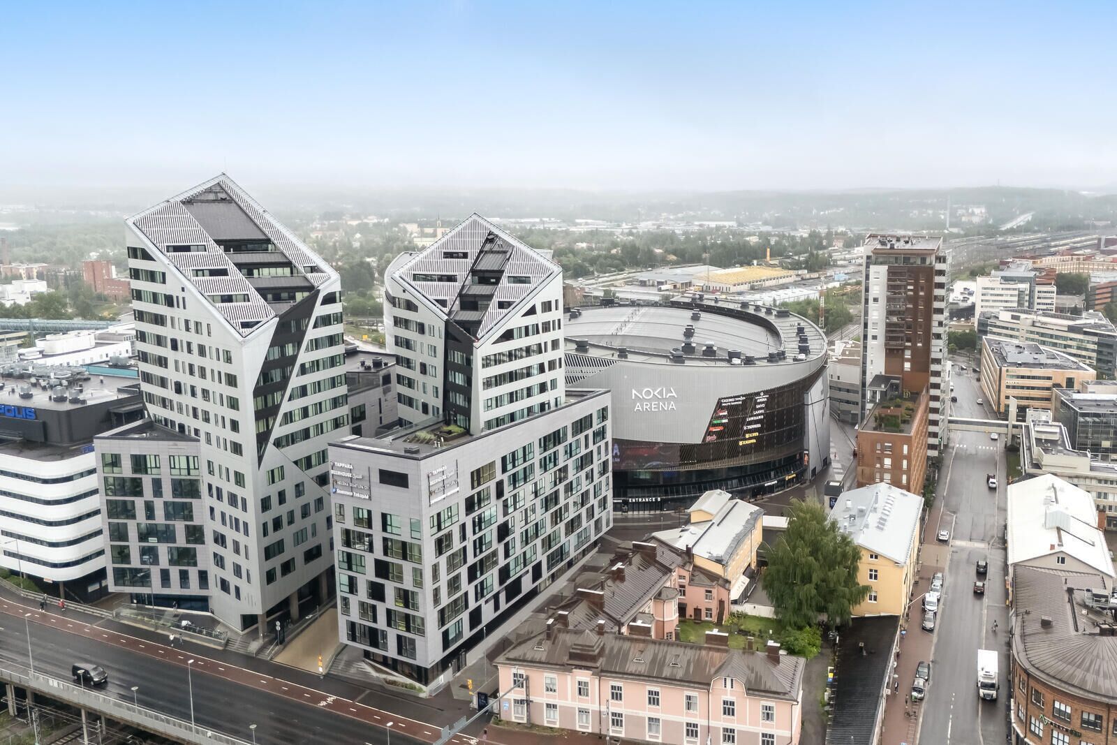 Una zona urbana moderna con un edificio curvo destacado identificado como 'Nokia Arena' y varios edificios altos adyacentes.