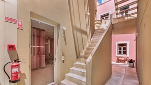 Ein schmaler Flur mit einer Treppe, die zu einer zweiten Etage führt. Ein Feuerlöscher ist an der Wand angebracht.