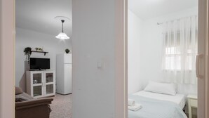 A bedroom with a bed, a nightstand, a television, a cabinet, and a ceiling light. - Apartment 'Flat Near Macarena Basilica' with Wi-Fi and Air Conditioning (Seville)