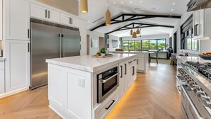 A modern kitchen with a large island, stainless steel appliances, and a view of the outdoors. - SERENITY ON SUNRISE~Canal Front 5 BR/5.5 Ba New Town Home w/ Pool & Dockage! (Key West)
