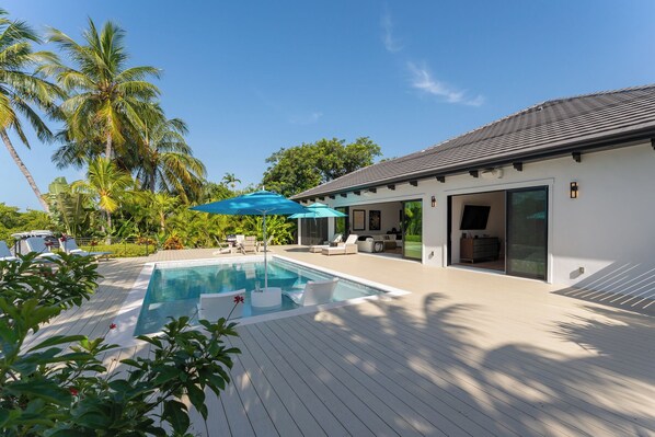 A modern house with a pool, outdoor furniture, and a covered patio area. - SERENITY ON SUNRISE~Canal Front 5 BR/5.5 Ba New Town Home w/ Pool & Dockage! (Key West)