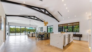 A spacious kitchen with a marble island, large windows, and a view of the outdoors. - SERENITY ON SUNRISE~Canal Front 5 BR/5.5 Ba New Town Home w/ Pool & Dockage! (Key West)